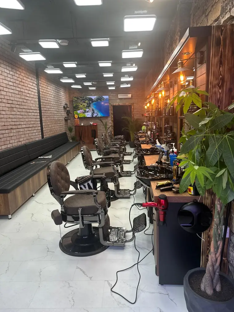 Barbershop interior at Galaxy Barber — brick walls, brass lamps and a row of chairs